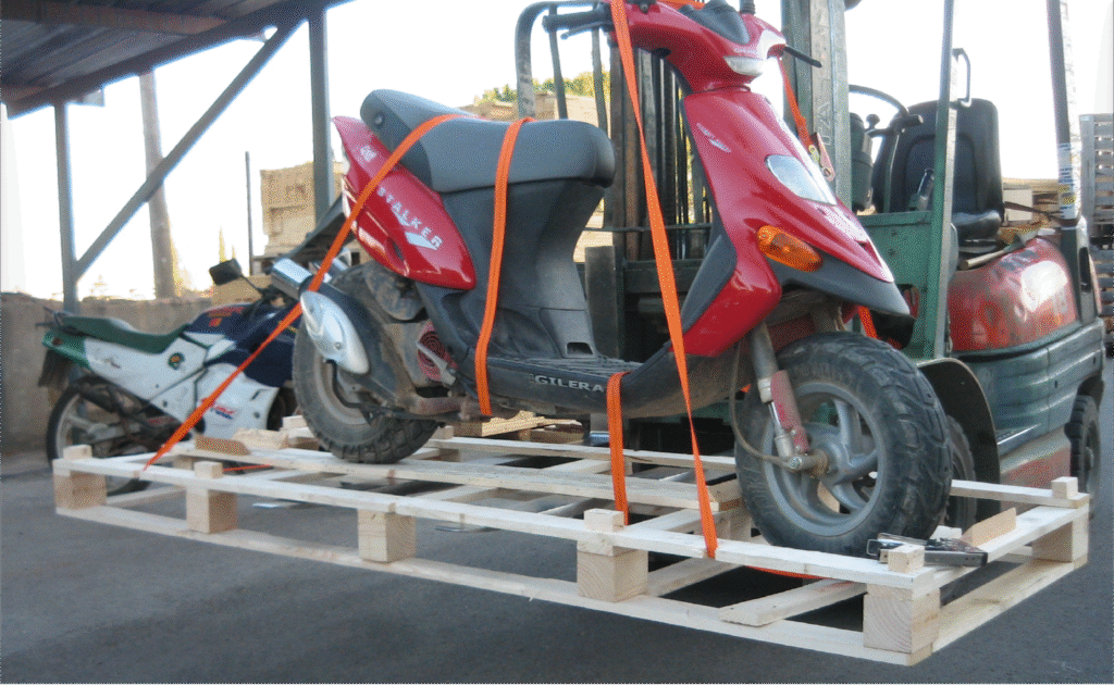Trincaje de cargas con cinchas para asegurar motocicleta sobre estructura de madera